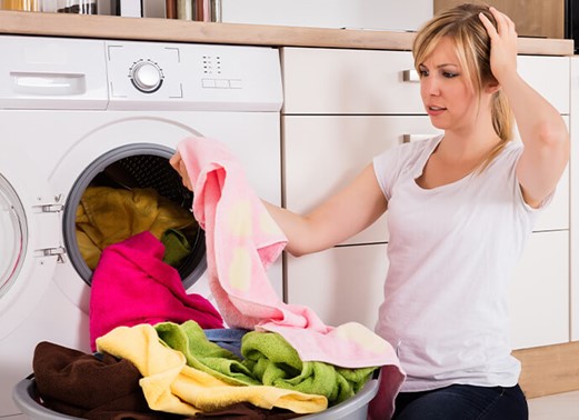 woman next to washing machine with piles of laundry