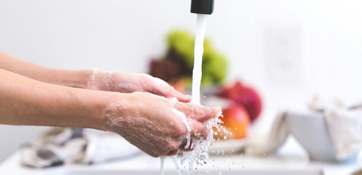 a close-up shot of someone washing their hands in a bright kitchen