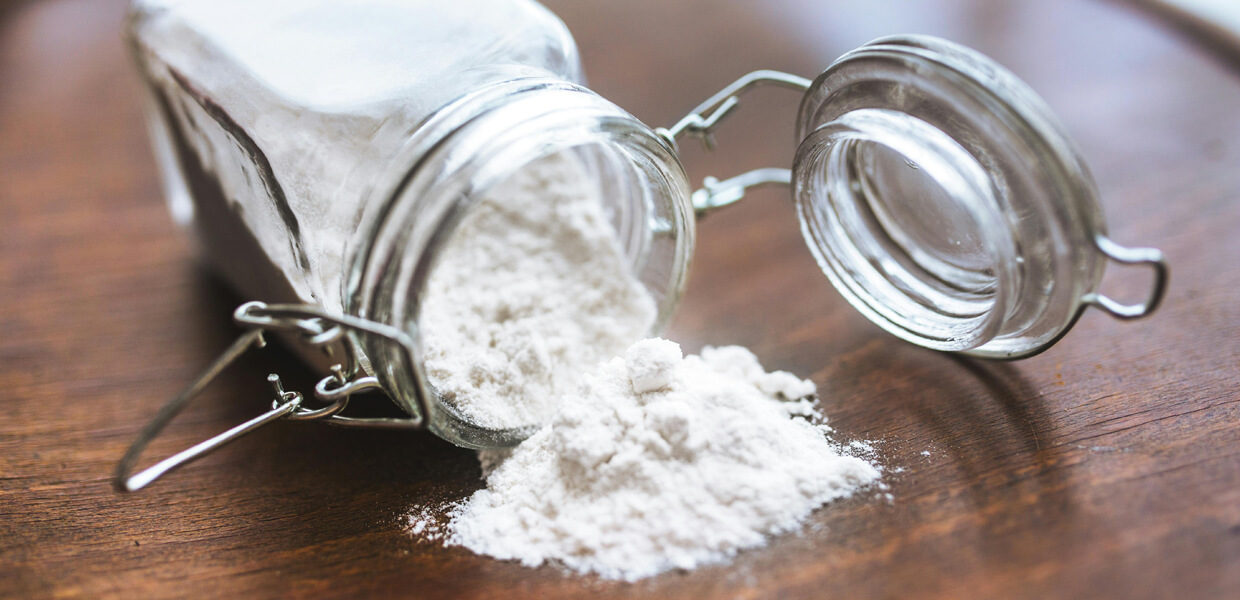 a close-up shot of a jar of baking soda on a dark wooden worktop