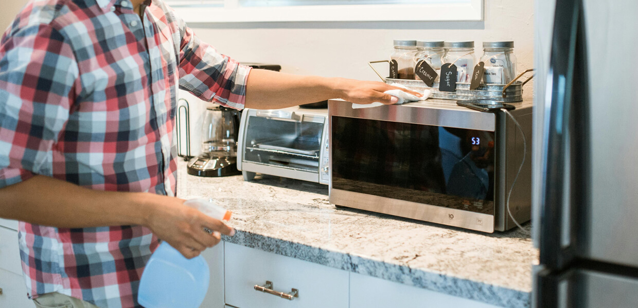 a man cleaning his free-standing microwave using a white cloth