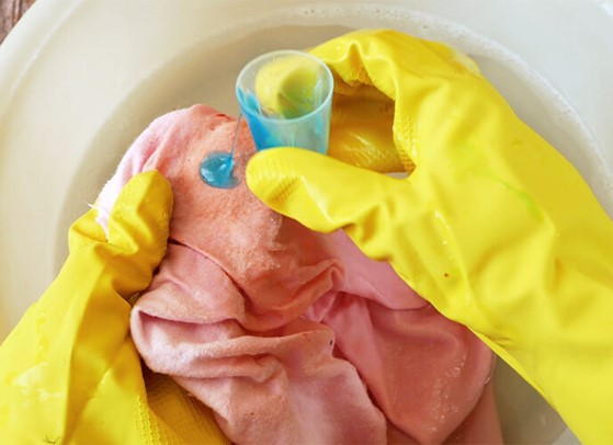 hands in yellow rubber gloves washing fabric